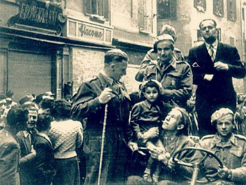 Liberazione di Bologna. Si sfila per via Rizzoli, passando davanti al Negozio Bongiovanni, si vedono le entrate degli altri negozi murate. L’unico esercizio rimasto aperto, con la sola serranda abbassata, è la ditta F. Bongiovanni, 21 aprile 1945