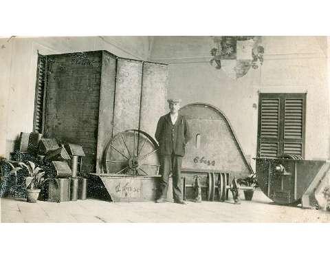Il fondatore dell'impresa Pietro Colombo in posa di fronte ad alcuni manufatti dell'officina, anni dieci
