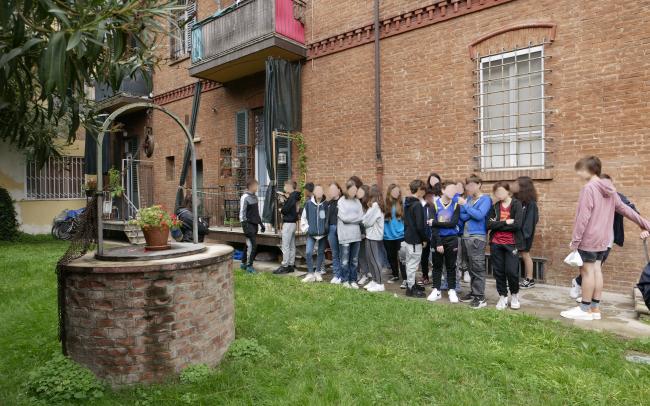 Una scolaresca visita l'insediamento in zona Andrea Costa. Nel cortile, il pozzo del primo edificio della Cooperativa costruito nel 1885